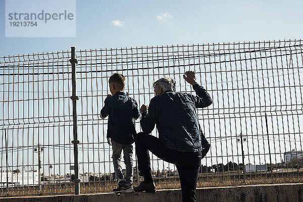 Grandfather and grandson looking through fence