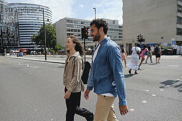 Happy man and woman walking together on street in city