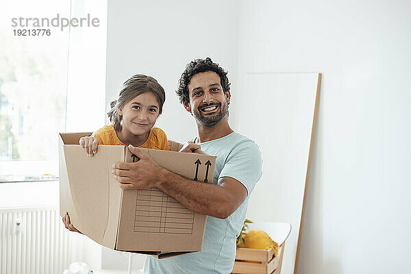 Glücklicher Mann mit Tochter  die zu Hause im Karton sitzt