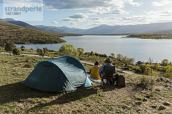 Couple looking at lake and camping on sunny day