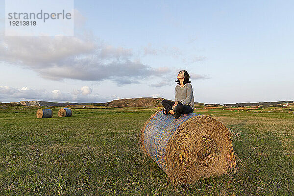 Frau sitzt auf Heu im Feld