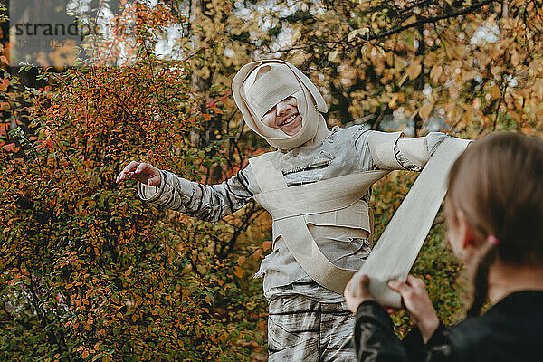 Mädchen hilft Freundin beim Tragen eines Halloween-Kostüms im Garten