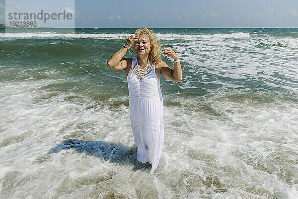 Senior woman wearing dress standing on shore at beach