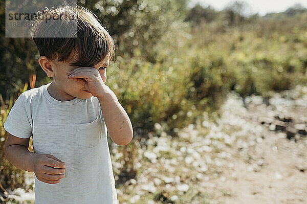 Trauriger Junge weint an einem sonnigen Tag im Feld