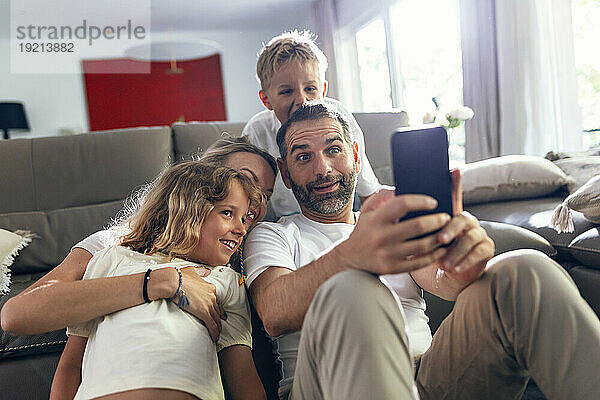 Reifer Mann macht zu Hause ein Selfie mit der Familie auf dem Handy