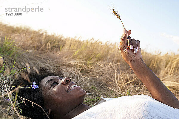 Happy young woman holding spikelet in field