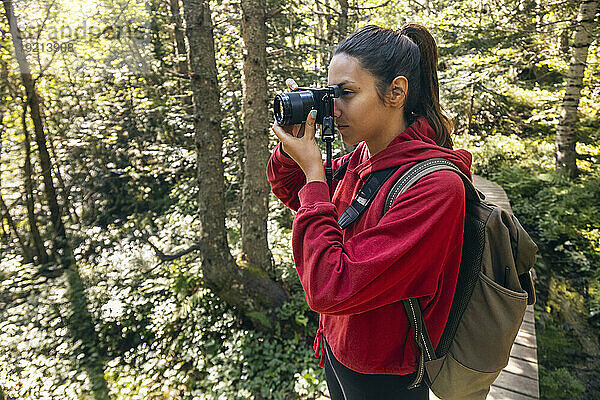 Junge Frau fotografiert mit Kamera im Wald