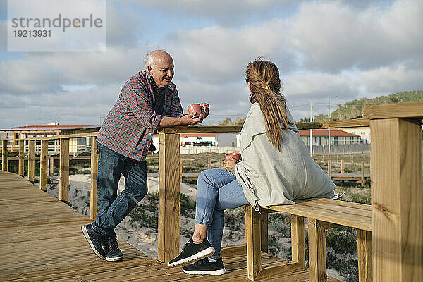 Glückliches älteres Paar mit Kaffeetassen  das gemeinsam Zeit auf der Promenade verbringt