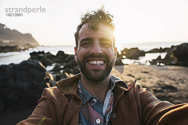 Glücklicher Mann  der bei Sonnenuntergang ein Selfie macht