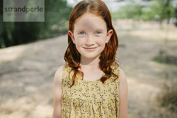 Lächelndes rothaariges Mädchen steht im Park