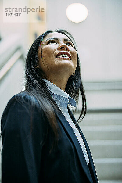 Lächelnde Geschäftsfrau schaut auf die Treppe im Büro