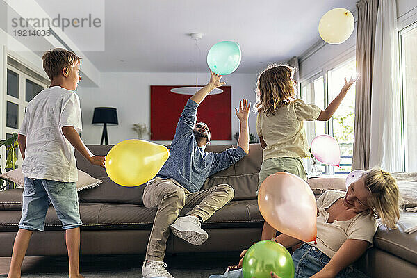 Eine glückliche Familie spielt gerne mit Luftballons im Wohnzimmer