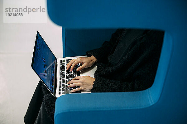 Businesswoman typing on laptop keyboard sitting in office