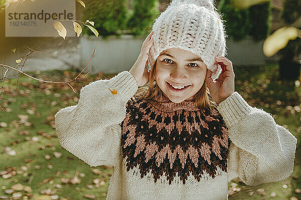 Smiling girl wearing knit hat standing in garden