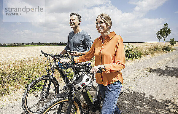 Mann hält Smartphone neben Frau  die Fahrrad auf Straße fährt