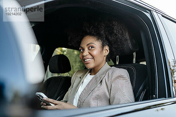Lächelnde Geschäftsfrau hält Smartphone im Auto