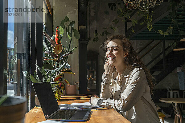 Glückliche junge Geschäftsfrau  die im Café sitzt