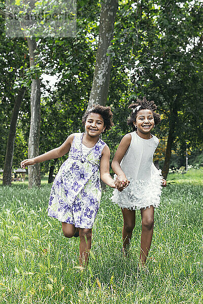Smiling twin sisters running in garden
