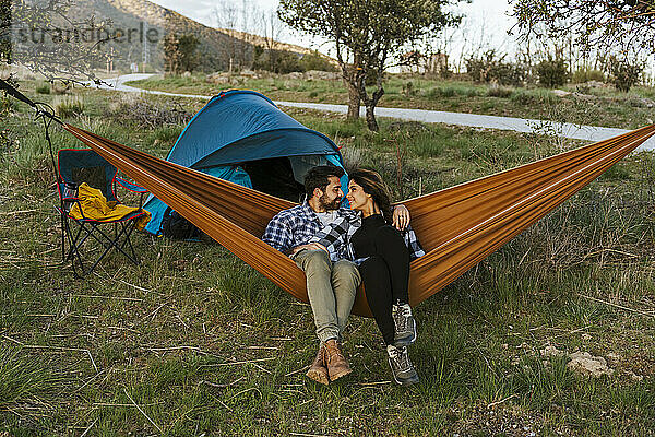 Romantic couple sitting in hammock near tent