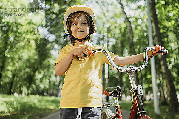 Junge steht mit Fahrrad im Park