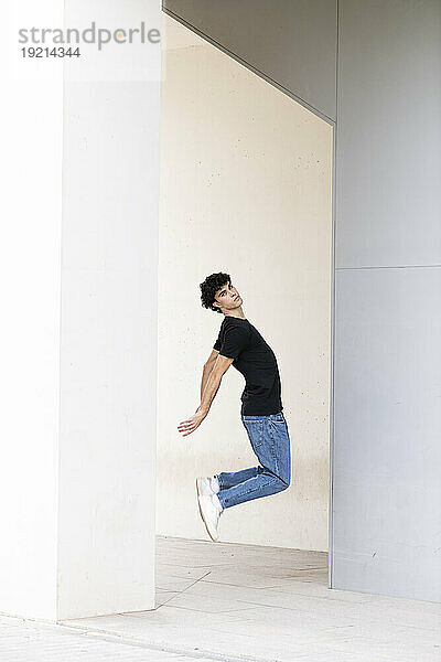 Young man jumping in front of white wall