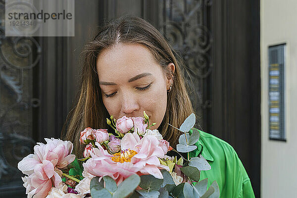 Woman smelling flowers in front of door