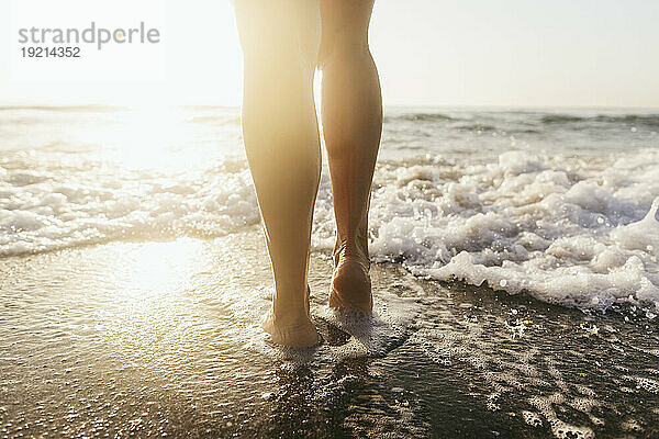 Frau geht an einem sonnigen Tag am Strand spazieren
