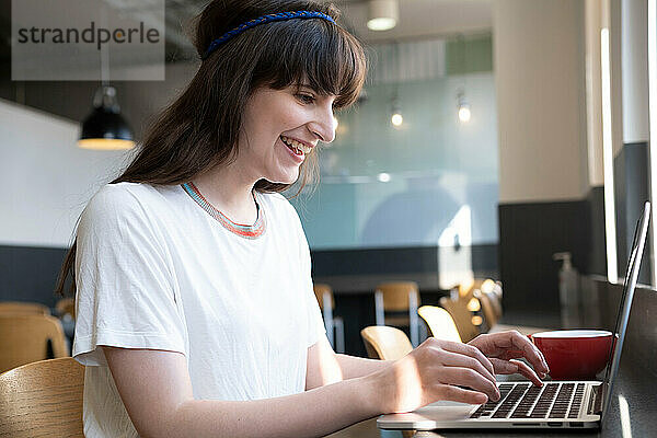 Glücklicher Freiberufler  der im Café am Laptop arbeitet