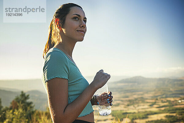 Schöne Frau hält Wasserflasche an einem sonnigen Tag