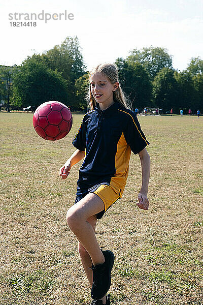 Smiling girl practicing soccer at sports field