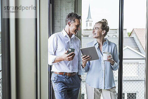 Glücklicher Geschäftsmann diskutiert mit Kollegen über Tablet-PC