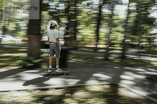 Junge fährt Skateboard auf Fußweg im Park