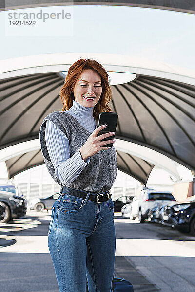 Glückliche Frau benutzt Smartphone auf Parkplatz
