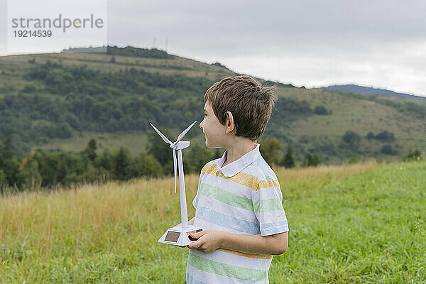 Junge mit Windturbinenmodell steht auf Gras