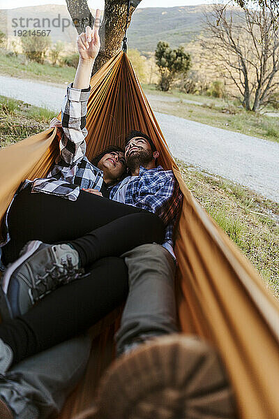Girlfriend and boyfriend spending leisure time lying down in hammock