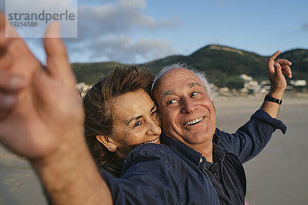 Glücklicher älterer Mann und Frau am Strand an einem sonnigen Tag