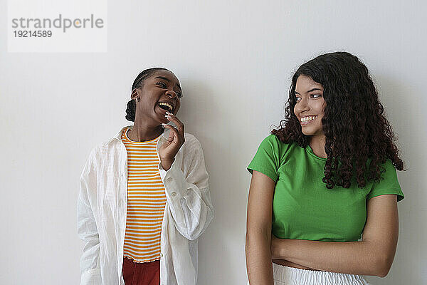 Young friends laughing in front of wall