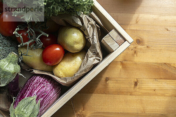 Fresh organic vegetables in crate on wooden table