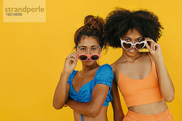 Gemischtrassige Freunde mit Sonnenbrille vor gelbem Hintergrund