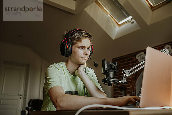 Teenager-Junge Podcasting vor dem Laptop zu Hause