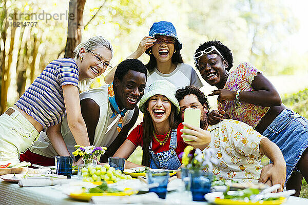 Lächelnde Freunde machen Selfie mit Smartphone am Picknicktisch