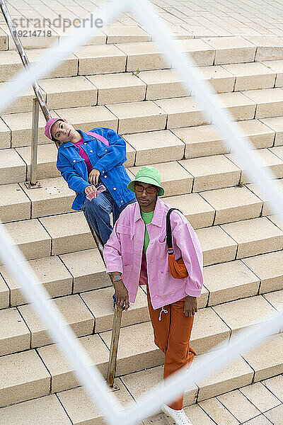 Multiracial friends standing on steps seen through frame