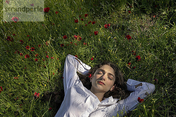 Frau entspannt sich auf Gras mit Mohnblumen
