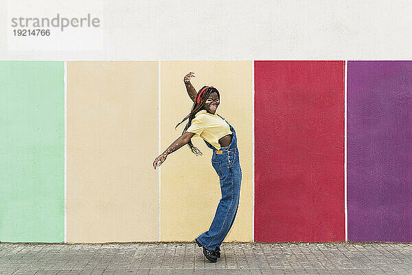 Glückliche Frau tanzt vor einer bunten Wand