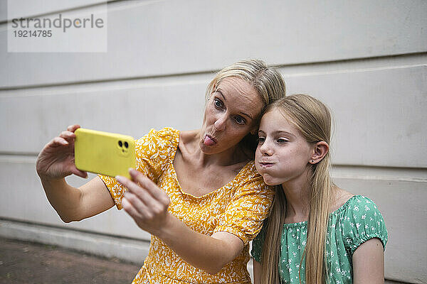 Mutter und Tochter schneiden Grimassen und machen Selfies mit dem Smartphone