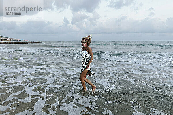 Blonde Frau im Kleid genießt den Strand