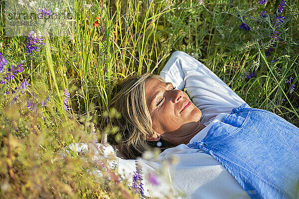 Frau mit geschlossenen Augen entspannt sich auf der Wiese