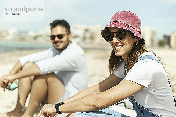 Lächelndes Paar sitzt am Strand