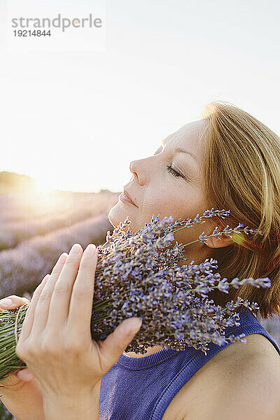 Ruhige Frau hält einen Strauß Lavendelblüten auf dem Feld