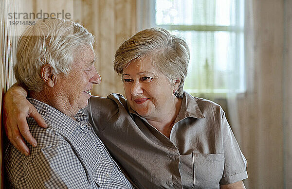 Senior couple with arm around in living room at home